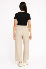 Pantalón ancho de tiro alto color crema, confeccionado en lino, con cintura elástica y cordón ajustable.