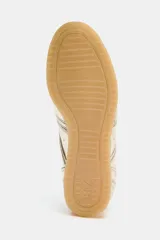 Zapatillas deportivas doradas con efecto metalizado. Cierre con cordones y suela de goma color caramelo.