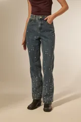 Pantalón jean azul de corte recto y calce alto, con bolsillos y detalles de strass.