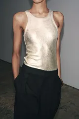 Body color crema de cuello redondo y sisas amplias. Tejido en rib metalizado con cierre inferior con broches a presión.