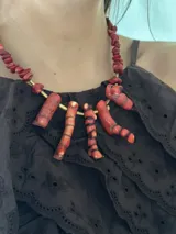 Collar corto con cuentas de coral rojo, bastones de bronce y cadena de acero quirúrgico con cierre de gancho ajustable.