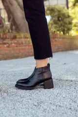 Botines negros de cuero con cierre lateral y taco geométrico.