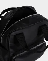 Mochila negra de cuerina con doble asa corta de mano con textura, correas regulables, cierre superior, bolsillo frontal con cierre, bolsillos laterales y tag en relieve.