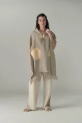 Chal con diseño a cuadros en tonos beige y marrón, con flecos en el borde inferior y apliques de cuero en la parte superior. Se abrocha con alamares de fieltro.