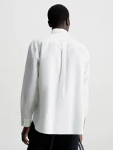 Camisa blanca de corte relaxed con cuello en punta, cierre de botones y bolsillo de parche en el pecho, hecha de mezcla de algodón y lino.