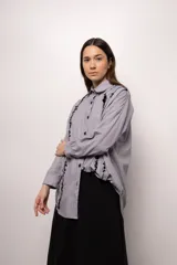 Camisa oversize a rayas grises y blancas, con bordado de mostacillas negras en cuello, frente y puños.
