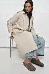 Zapato plano tipo mule destalonado confeccionado en serraje color marrón, con detalle de pespunte en el cuerpo y punta redonda.