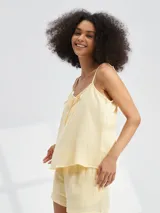 Musculosa color amarillo pálido con tirantes finos y detalle de lazo en el escote.
