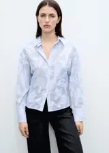 Camisa celeste a rayas verticales con bordado de flores blancas, de corte oversize, manga larga y cuello camisero.