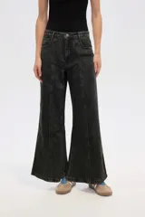 Pantalón de jean de tiro alto, color negro lavado, con corte ancho y acampanado (flare). Presenta costuras verticales marcadas en el frente de cada pierna.