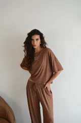 Conjunto de dos piezas color crema, compuesto por una remera de mangas cortas con logo bordado en el pecho y un pantalón palazzo con cintura elastizada y cordón ajustable.