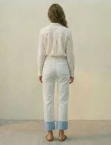 Jean de algodón de tiro medio, color celeste muy claro, con un dobladillo ancho y contrastante en color azul claro en los tobillos. El corte es recto o ligeramente holgado.