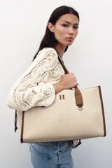 Bolso maxi shopper de hombro color beige con detalles en cuero marrón. Tiene doble asa de cuero y bolsa de tela extraíble con cierre fruncido.