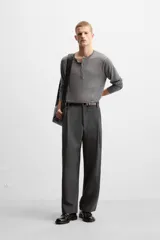 Pantalón relaxed fit color verde oscuro, con pliegues en la parte delantera, bolsillos laterales y traseros de ojal. Cierre frontal con cremallera y botón.