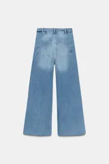 Jeans de tiro alto, pierna ancha y largo al tobillo, en denim celeste claro con efecto lavado. Presenta costura marcada en el centro de cada pierna y cierre frontal con cremallera y botón.