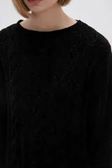Sweater marrón de punto con textura trenzada, cuello redondo y mangas largas.