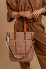 Cartera tipo tote de color negro con diseño de gran capacidad. Presenta asas dobles fijas, una correa de hombro ajustable y extraíble, y un bolsillo frontal plano. Está confeccionada en material sintético con acabado liso.