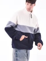 Buzo de polar con cierre parcial y cuello alto, con diseño a bloques de color: blanco, gris y azul marino.