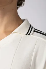 Remera tejida color crudo con cuello tipo chomba en V, mangas cortas con rayas negras y estampado con letras en el frente. Confeccionada en hilado de algodón.