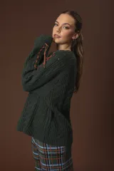 Sweater verde oscuro de punto trenzado con cuello redondo y mangas largas con detalle de costuras cruzadas en color naranja.