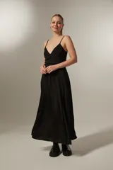 Vestido largo negro con breteles finos, escote en V y falda amplia con frunce en la cintura.