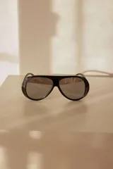 Lentes de sol estilo aviador con montura gruesa de policarbonato negro y cristales espejados grises.