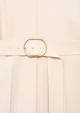 Mono largo color crema, con cuello de pico, manga corta y cinturón con hebilla. Cierre de cremallera en la parte posterior.