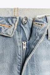 Pantalón de jean celeste de tiro alto con cintura doblada, cinco bolsillos, efecto lavado y roturas.