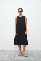 Vestido negro sin mangas, de corte recto y largo a la rodilla.