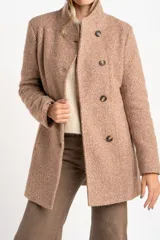 Tapado de poliéster con textura en color beige, de calce al cuerpo. Cuenta con cuello alto, cierre frontal de botones oscuros y bolsillos laterales.