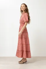 Maxi vestido rojo con estampado de rombos, corte camisero, cuello clásico, mangas cortas abullonadas con puños elásticos, cintura elastizada y falda larga escalonada.