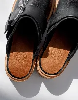 Mocasines negros de cuero con hebilla plateada y suela de cuero color natural.