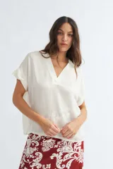 Blusa de corte suelto con escote en forma de V, color crudo y mangas cortas.