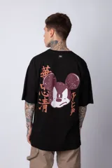 Remera blanca de algodón de corte oversize con mangas cortas y cuello redondo. Presenta un pequeño estampado en el frente con la figura de Mickey Mouse y caracteres orientales.