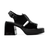 Sandalias de cuero sintético negro con plataforma y tacón bloque. Presentan una tira ancha sobre el empeine con aberturas geométricas y pulsera con hebilla al tobillo.