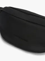 Riñonera negra Tommy Hilfiger con logo metálico en el frente, correa ajustable con cierre de apertura fácil, panel de malla acolchado en la parte trasera y bolsillo interior con cremallera. Confeccionada en poliéster.