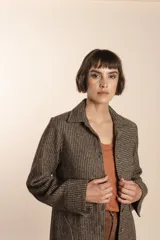 Camisa larga color crema con rayas verticales finas en gris, con botones dorados y bolsillo plaque en la delantera.