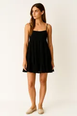 Vestido corto negro de algodón con breteles finos, escote recto y falda escalonada.