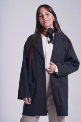 Tapado gris oscuro de corte oversize, con solapa clásica, hombros caídos, cierre con un botón central y bolsillos laterales funcionales.