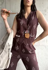 Chaleco marrón con estampado de rombos blancos, cuello en V y cierre frontal con botones.