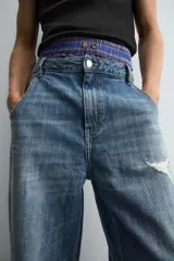 Pantalón de jean azul de corte amplio, con roturas y lavado gastado.
