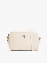 Bandolera Tommy Hilfiger color crema con monograma TH en relieve. Tiene correa ancha ajustable y extraíble, cierre de cremallera, bolsillo interior con cremallera y monedero extraíble con cremallera.