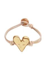 Pulsera ajustable de cordón de cuero color beige/camel con un dije central de corazón dorado de aspecto martillado. Presenta un cierre de bola dorada ajustable.