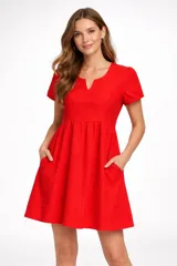 Vestido corto negro de broderie, con mangas cortas abullonadas y escote en V. Presenta un corte imperio con frunce en la cintura y falda acampanada.