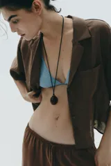 Camisa marrón de cuello solapa y escote pico con manga corta. Bolsillos de plastrón en pecho. Cierre frontal con botones.