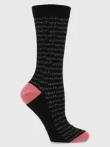 Calcetín largo negro con texto repetido "Hush Puppies" en gris claro. El talón y la punta son de color rosado.