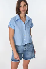 Camisa color beige de lino, con cuello clásico, manga corta con detalle de frunce y bolsillo de parche en el pecho.