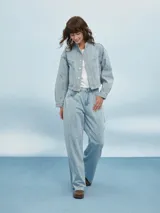 Campera de jean azul claro con cuello mao, cierre con botones metálicos y costuras a contraste.