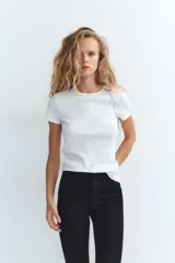Jeans skinny de tiro alto en denim azul oscuro, con cinco bolsillos y cierre frontal con cremallera y botón metálico.
