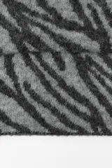 Bufanda rectangular de punto con estampado de cebra en tonos grises y negros.